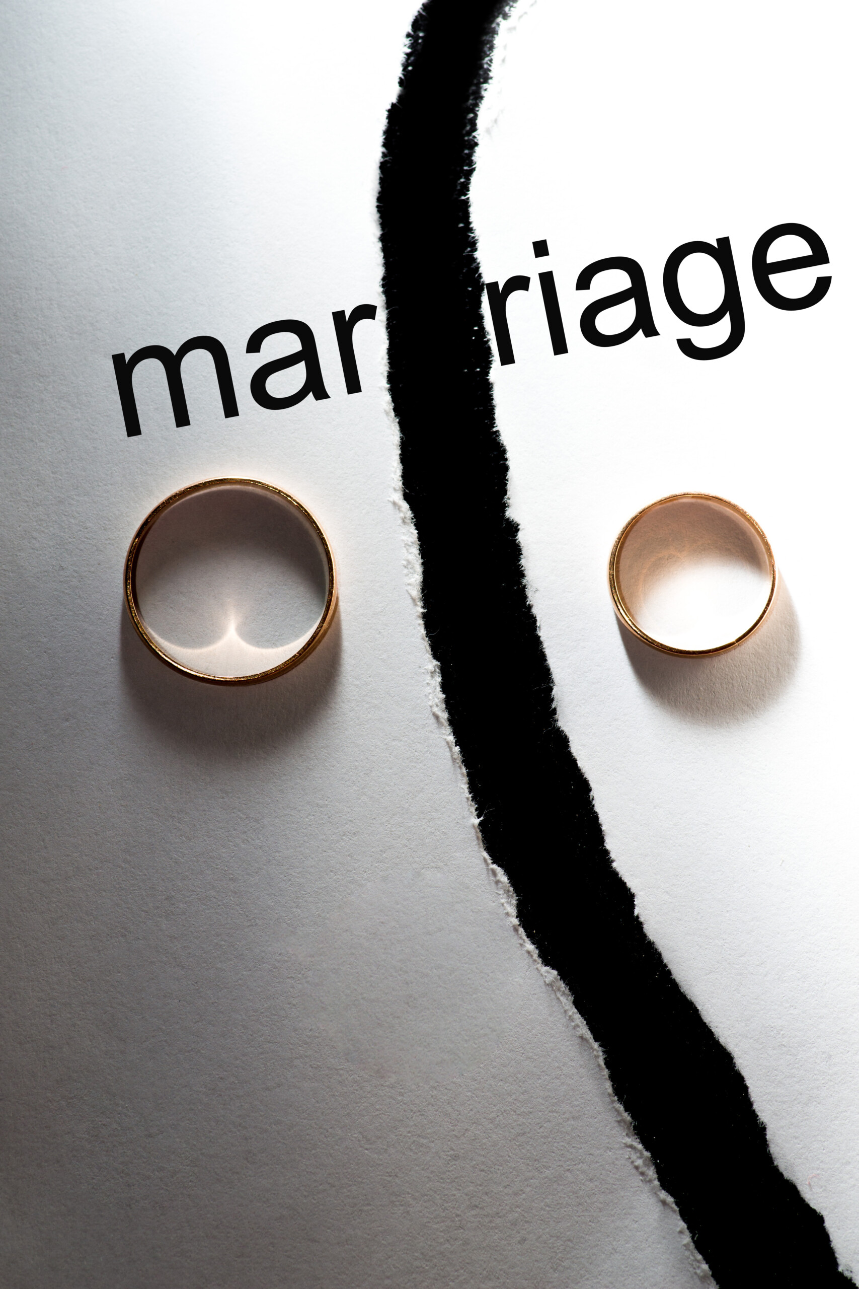 Wedding rings on different halves of a torn sheet of paper. Broken word marriage
